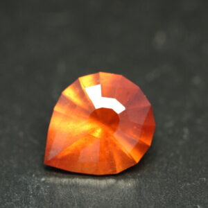 Macrofoto van een oranje spessartietgranaat van 5,3 karaat met een Aqua Drop-slijping op een zwarte leisteen.