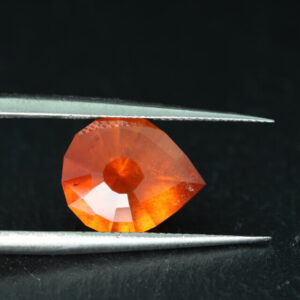 Macrofoto van een oranje spessartietgranaat van 5,3 karaat met een Aqua Drop-slijping op een zwarte leisteen.